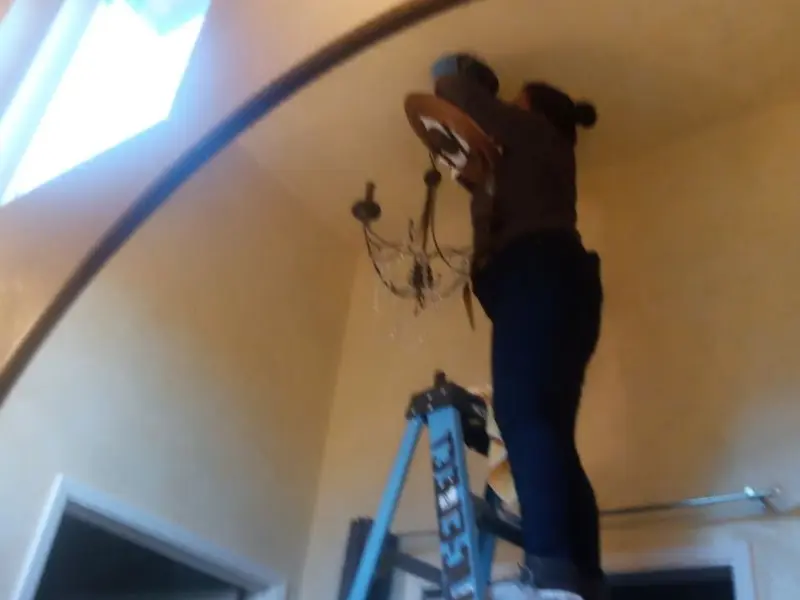 Electrician installing a chandelier in a Bellview residence